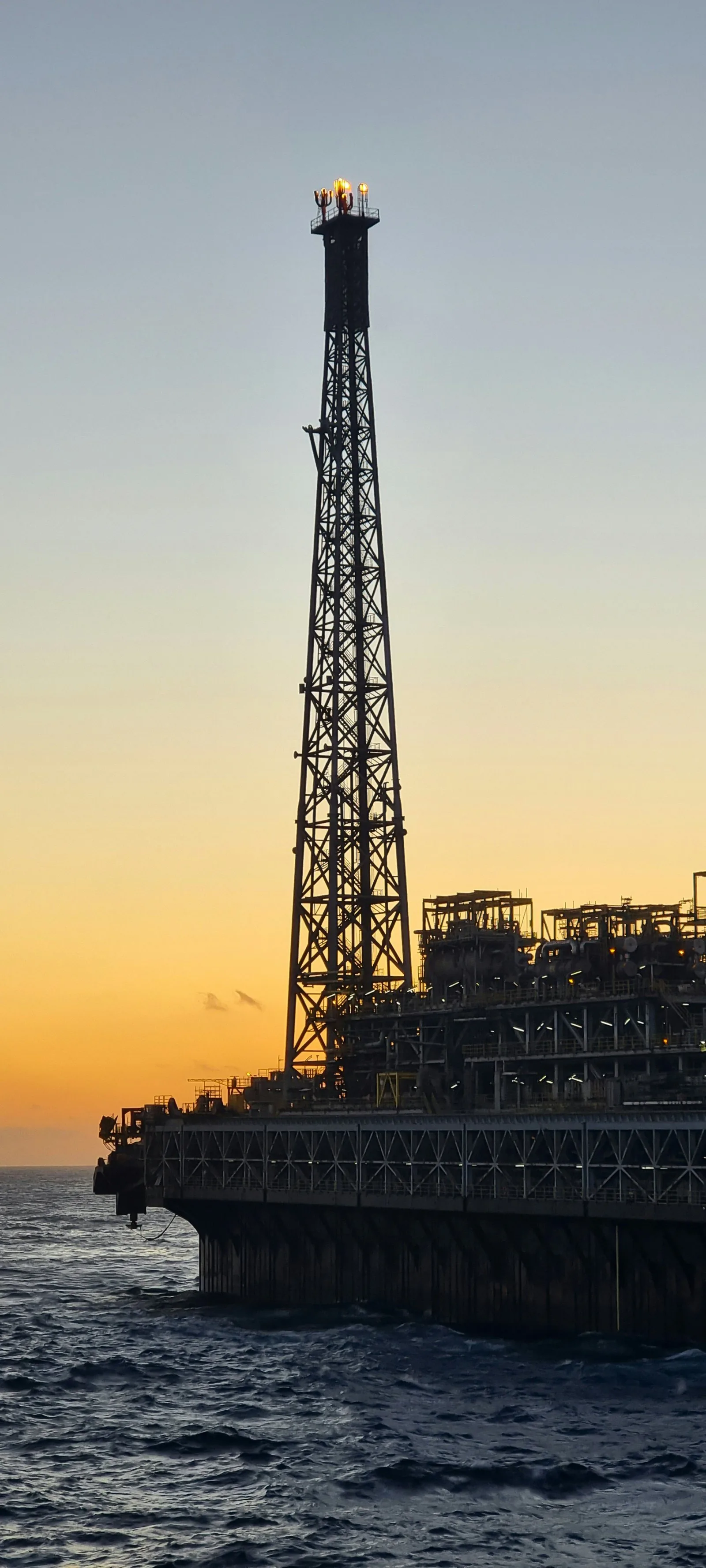 Flare tower silhouetted at sunset